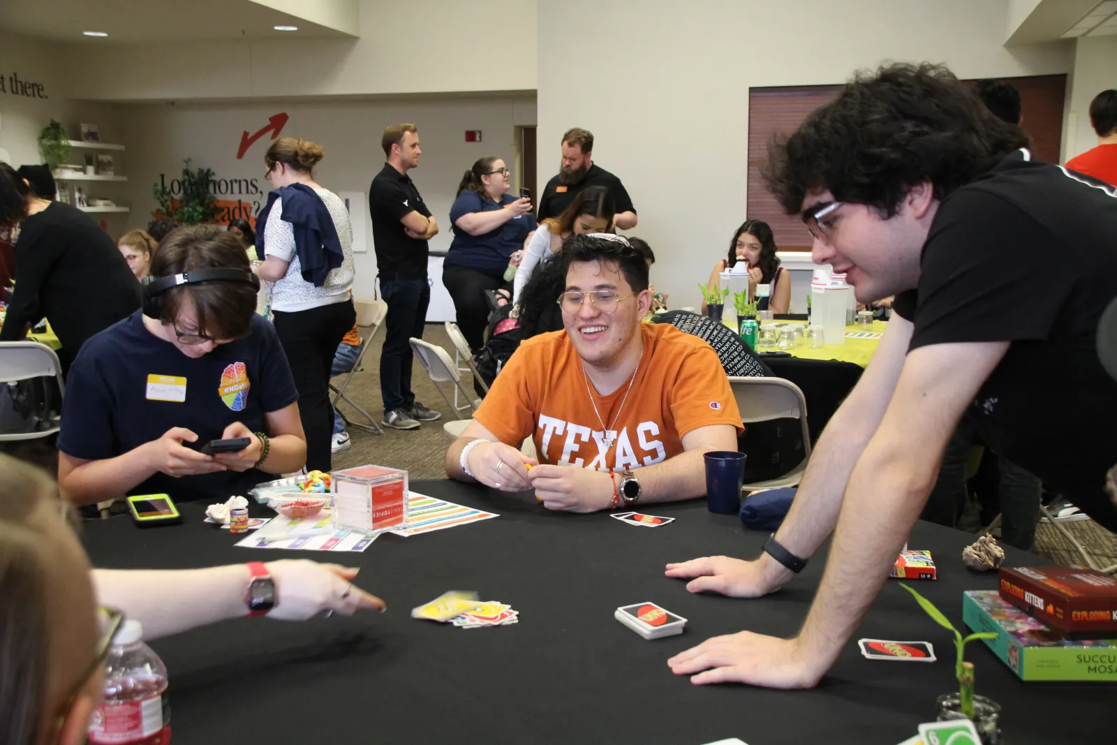 students gathered around a table. A Student is smiling while playing a board game.