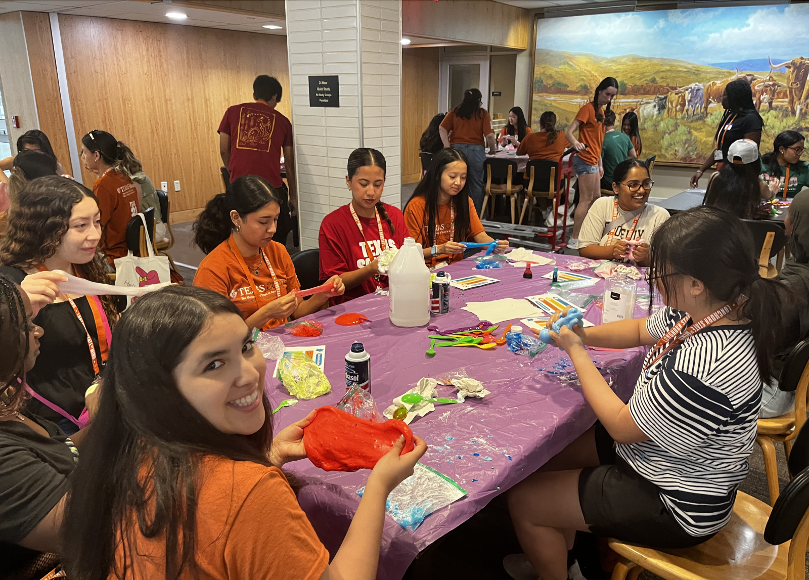 students at a table making slime. One student is smiling at the camera with slime in her hands.