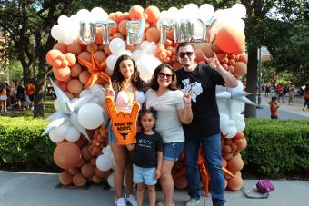 Family posing in front off balloons that say "UT Family"