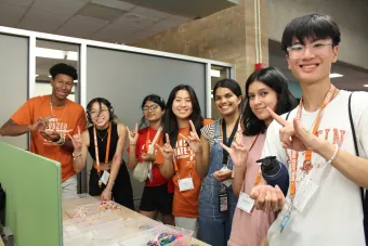 students posing together with a hookem horns