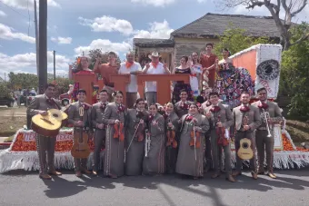 Student mariachi band stands beside their parade float