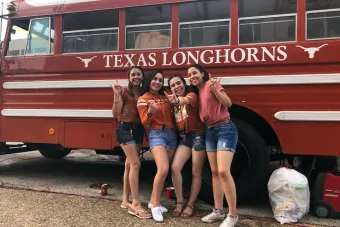 Four student post in front of the Texas Longhorns bus