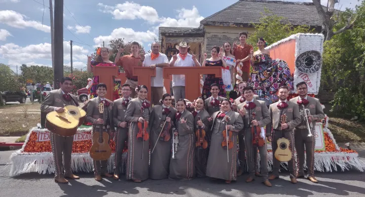 Student mariachi band stands beside their parade float