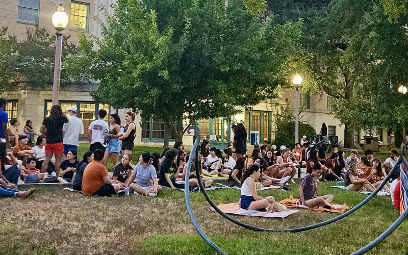 students gathered on a lawn watching a movie