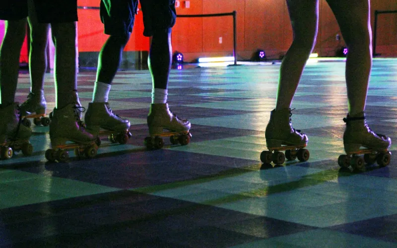 people on Rollerskates skating across the checkered designed floor.